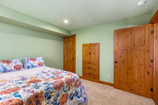 carpeted bedroom featuring a textured ceiling and baseboards