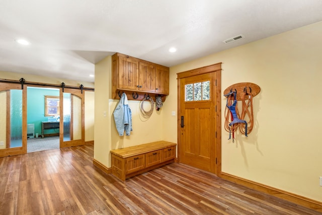 mudroom with a barn door, visible vents, recessed lighting, and wood finished floors