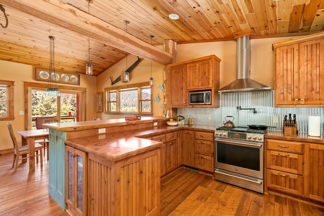 kitchen featuring pendant lighting, tasteful backsplash, appliances with stainless steel finishes, wall chimney range hood, and a peninsula