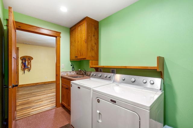 clothes washing area featuring cabinet space, baseboards, washer and dryer, and a sink