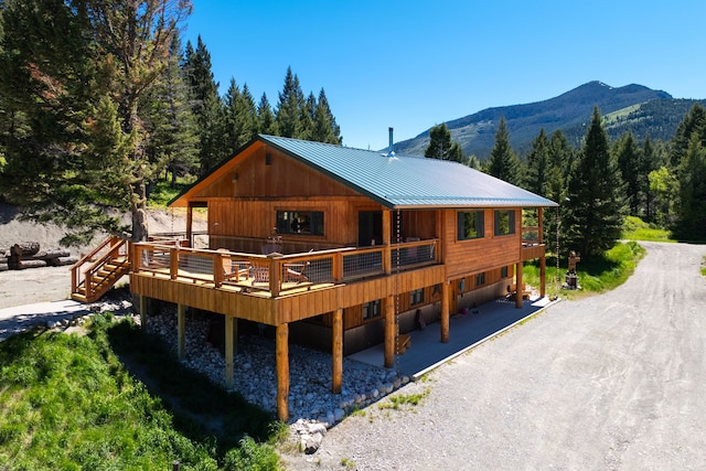 rear view of house featuring a standing seam roof, metal roof, and a deck with mountain view