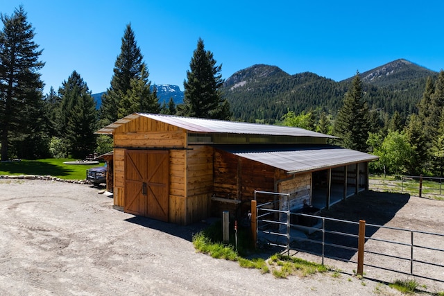 view of stable with a mountain view and a view of trees