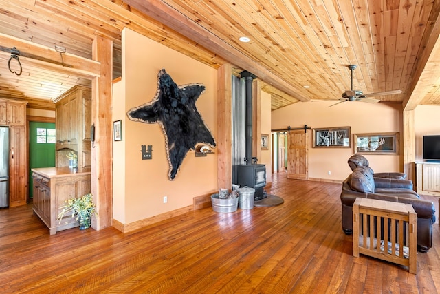 living area with baseboards, lofted ceiling, wooden ceiling, wood-type flooring, and a wood stove