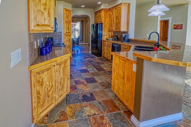 kitchen with sink, black fridge, kitchen peninsula, pendant lighting, and backsplash