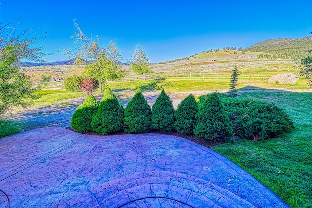 view of yard featuring a patio, a mountain view, and a rural view