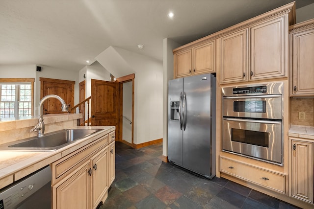 kitchen featuring sink, stainless steel appliances, light brown cabinetry, and tasteful backsplash