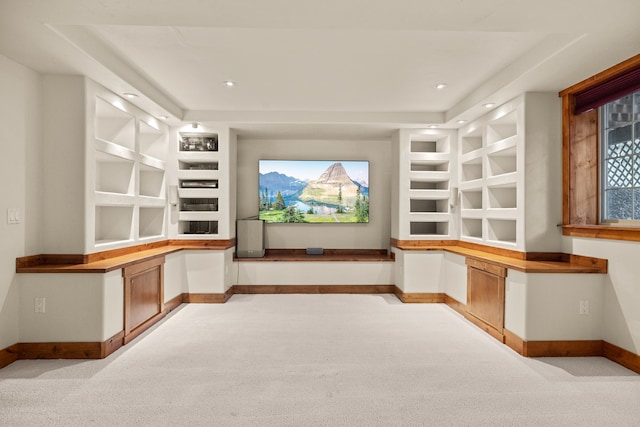 home theater room with built in shelves and light colored carpet