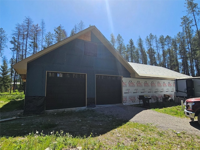 view of side of home with an attached garage and gravel driveway