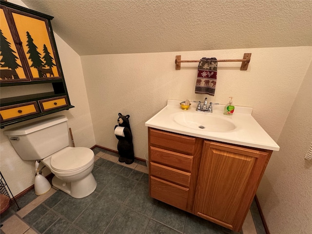 bathroom featuring vaulted ceiling, tile patterned flooring, a textured ceiling, toilet, and vanity