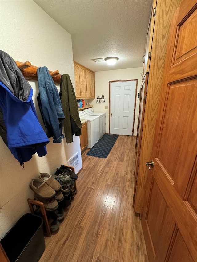 interior space with washing machine and clothes dryer, light wood-type flooring, and a textured ceiling