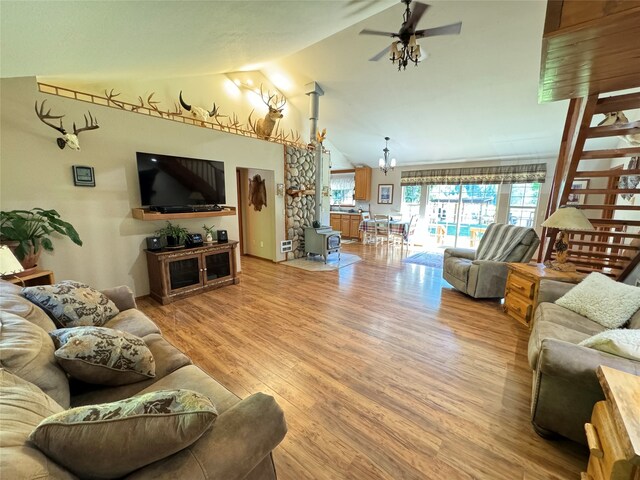 living room featuring ceiling fan with notable chandelier, light hardwood / wood-style flooring, and vaulted ceiling