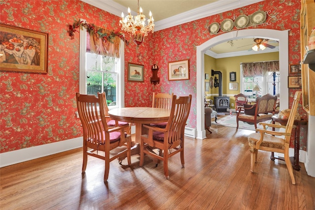 dining space featuring plenty of natural light, wood-type flooring, a wood stove, and crown molding