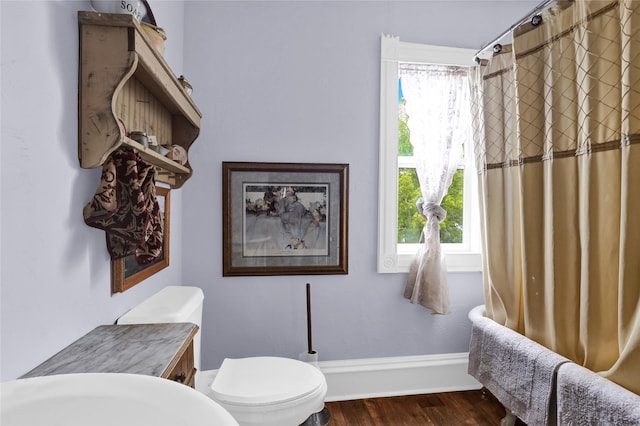 bathroom with a shower with curtain, toilet, and wood-type flooring