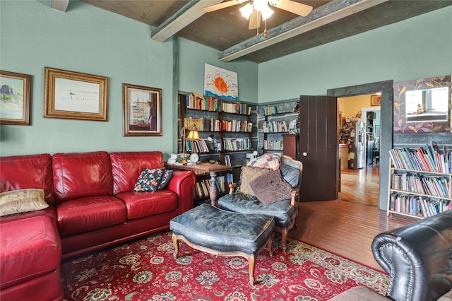 living room featuring ceiling fan, hardwood / wood-style floors, and beamed ceiling