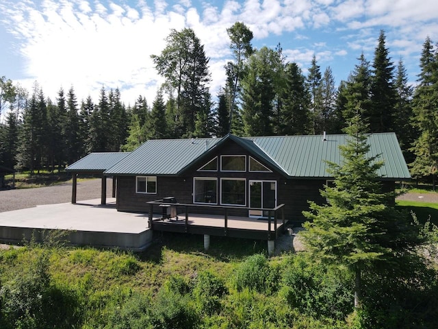 rear view of property featuring metal roof, a deck, and a standing seam roof