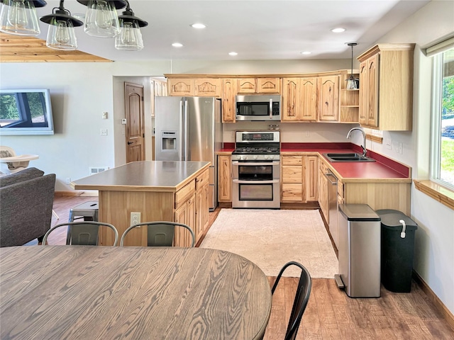 kitchen with stainless steel appliances, hanging light fixtures, a sink, and a healthy amount of sunlight