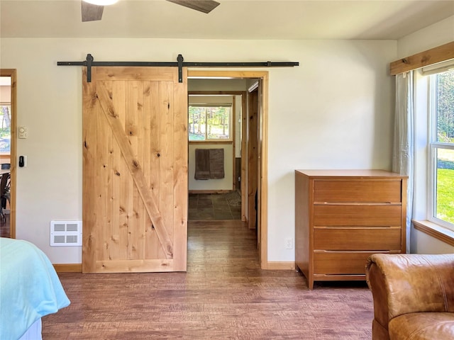 bedroom featuring dark wood-style flooring, baseboards, and a barn door