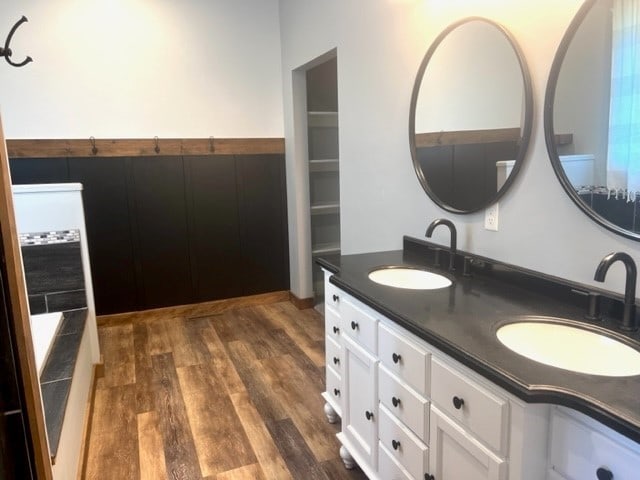 bathroom with a bath, vanity, and wood-type flooring