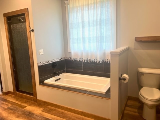 bathroom featuring hardwood / wood-style flooring, toilet, and plus walk in shower