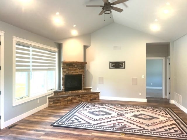 unfurnished living room with ceiling fan, a fireplace, wood-type flooring, and lofted ceiling