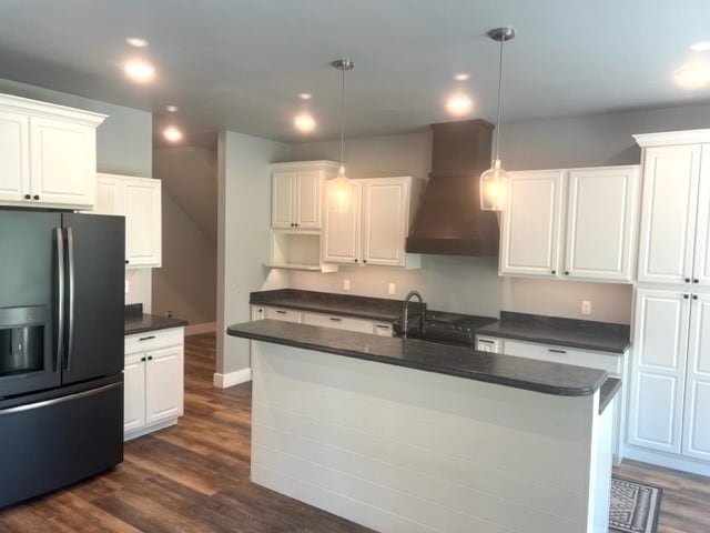 kitchen featuring premium range hood, white cabinets, pendant lighting, and stainless steel refrigerator with ice dispenser