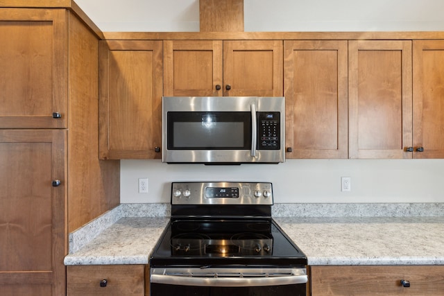 kitchen featuring appliances with stainless steel finishes and light stone counters