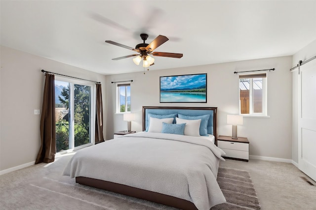 bedroom featuring ceiling fan, light colored carpet, and a barn door