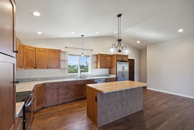 kitchen with butcher block countertops, appliances with stainless steel finishes, decorative light fixtures, vaulted ceiling, and a kitchen island