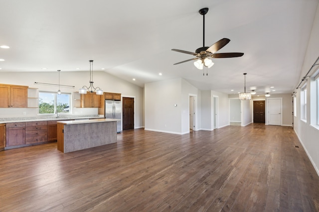 kitchen featuring ceiling fan with notable chandelier, stainless steel refrigerator, pendant lighting, and a kitchen island