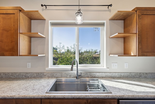 kitchen with dishwasher, light stone countertops, sink, and pendant lighting