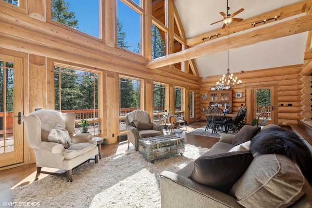 living room featuring log walls, ceiling fan with notable chandelier, hardwood / wood-style flooring, and high vaulted ceiling