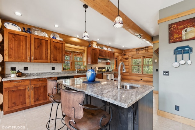 kitchen featuring sink, stainless steel range oven, pendant lighting, a kitchen bar, and a center island with sink