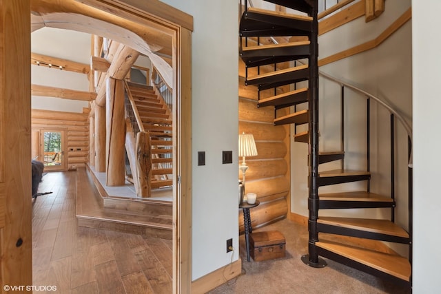 staircase with log walls and wood-type flooring