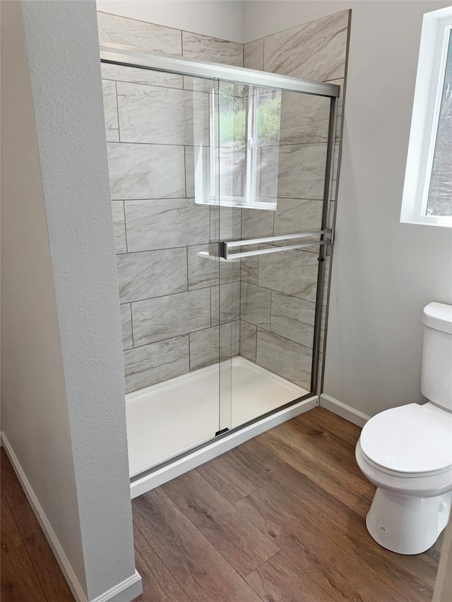 bathroom featuring hardwood / wood-style floors, toilet, and a shower with door