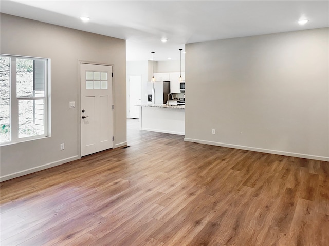 unfurnished living room with sink, a healthy amount of sunlight, and hardwood / wood-style floors