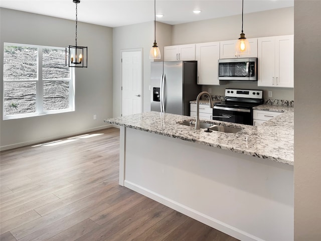 kitchen featuring light hardwood / wood-style flooring, stainless steel appliances, white cabinets, pendant lighting, and sink