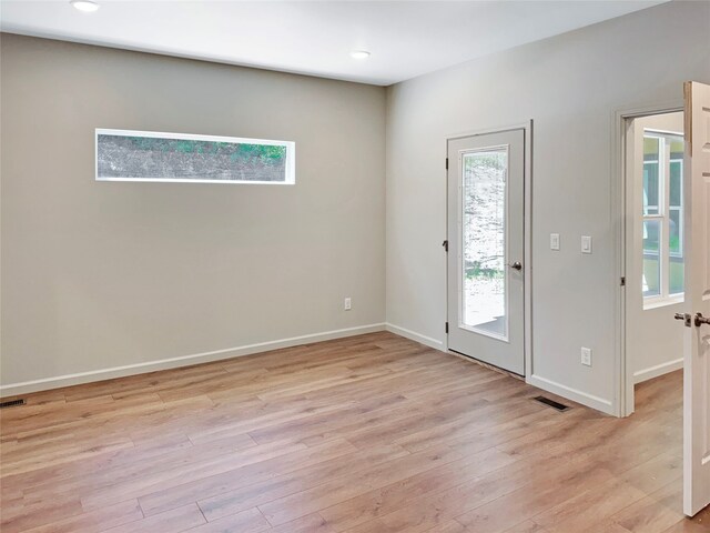 empty room with plenty of natural light and light hardwood / wood-style floors