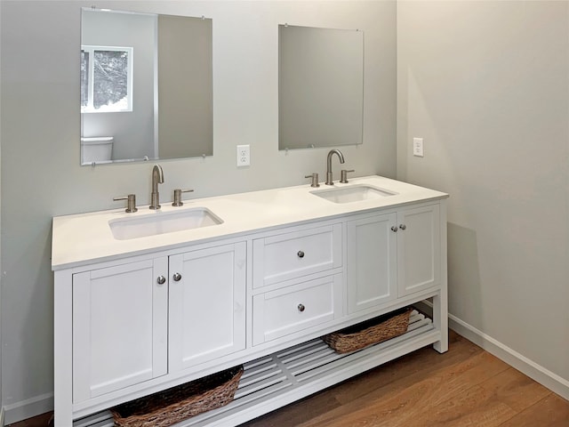 bathroom featuring toilet, double sink vanity, and wood-type flooring