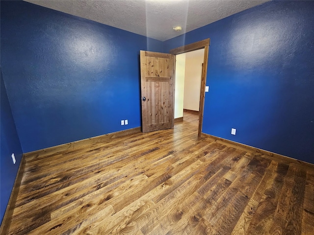 empty room with wood-type flooring and a textured ceiling