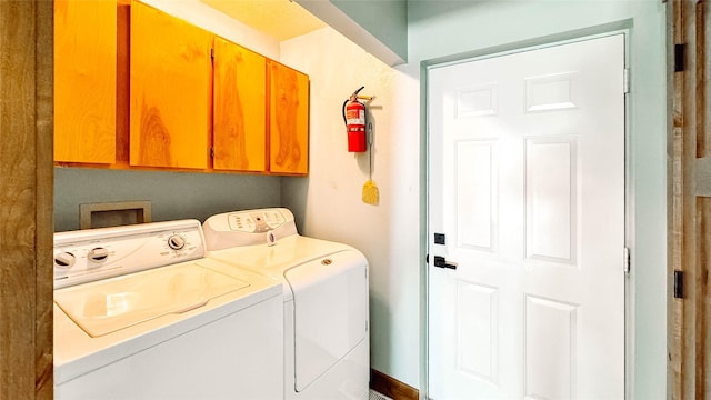 clothes washing area featuring cabinets and separate washer and dryer