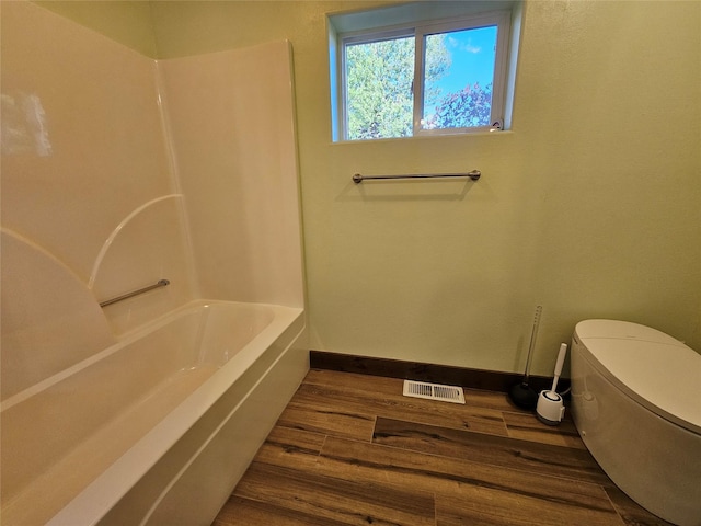 bathroom featuring hardwood / wood-style flooring, a bathing tub, and toilet