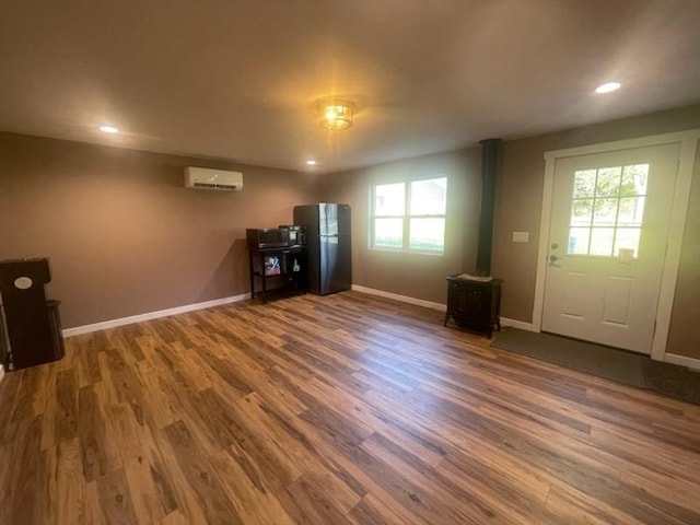 interior space with an AC wall unit, a wood stove, a wealth of natural light, and dark hardwood / wood-style floors