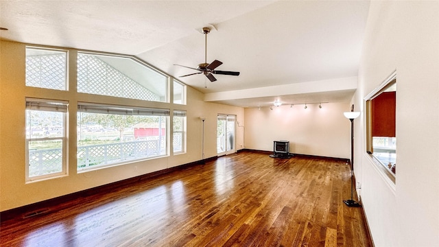 unfurnished living room with vaulted ceiling, dark hardwood / wood-style floors, heating unit, a wood stove, and ceiling fan