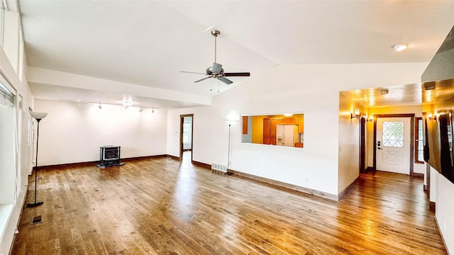 unfurnished living room featuring lofted ceiling, a wood stove, hardwood / wood-style floors, and ceiling fan