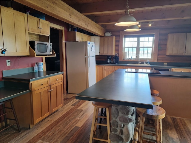 kitchen with hardwood / wood-style floors, white refrigerator, sink, decorative light fixtures, and beam ceiling