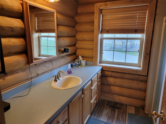 bathroom with log walls, vanity, and hardwood / wood-style flooring