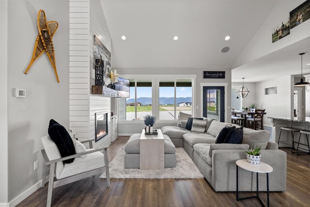 living room featuring dark wood-type flooring, a large fireplace, a mountain view, and high vaulted ceiling