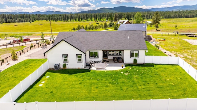 back of property with a yard, a mountain view, and a patio area