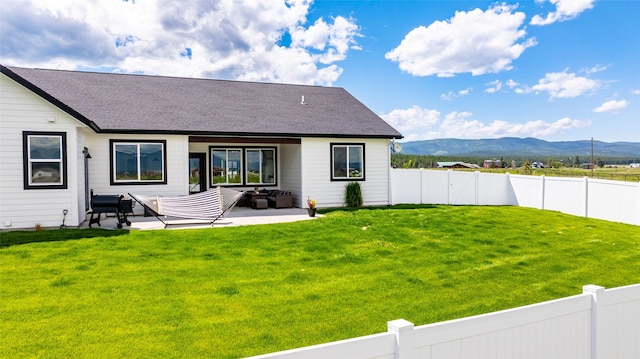 back of house with a patio, a mountain view, and a lawn