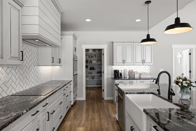 kitchen featuring pendant lighting, sink, dark stone countertops, backsplash, and stainless steel appliances